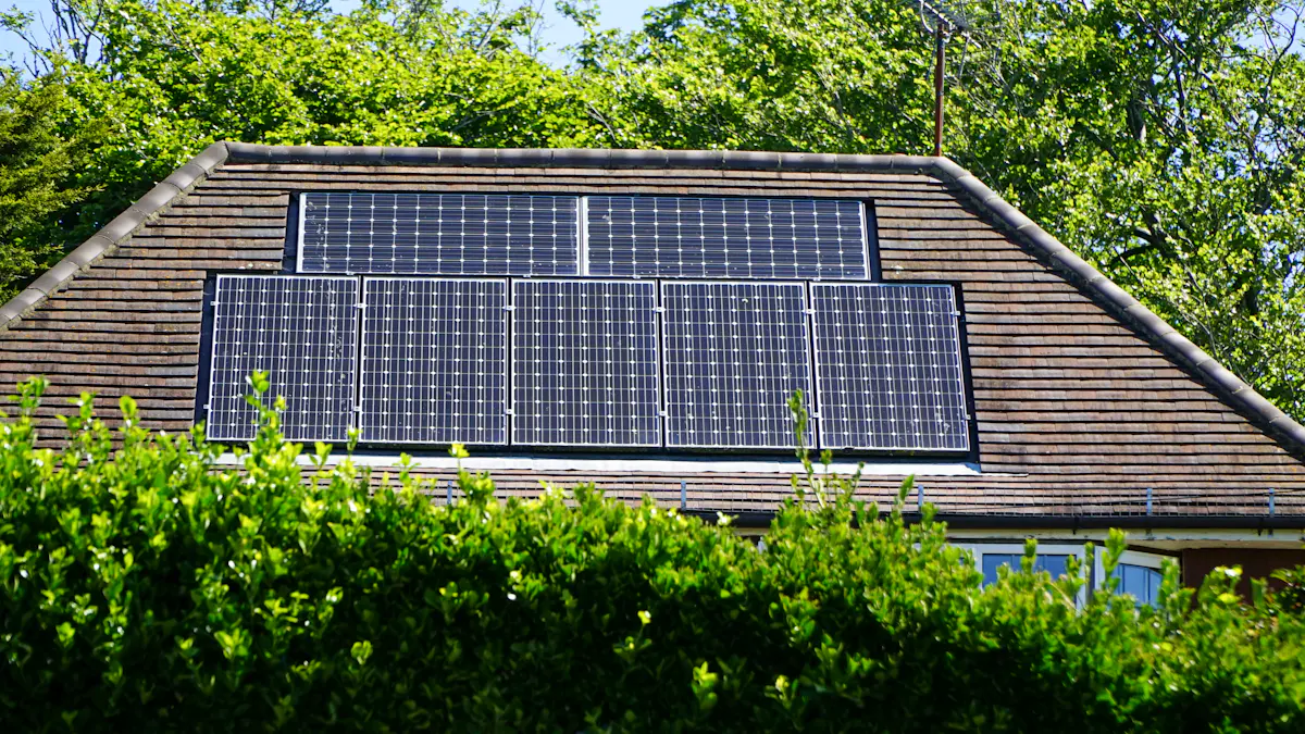 Hausdach mit einer kleinen Photovoltaikanlage hinter einer Hecke
