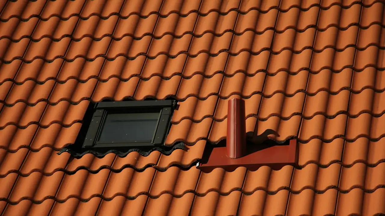 Rotes Ziegeldach mit Dachfenster und LĂĽftungsrohr