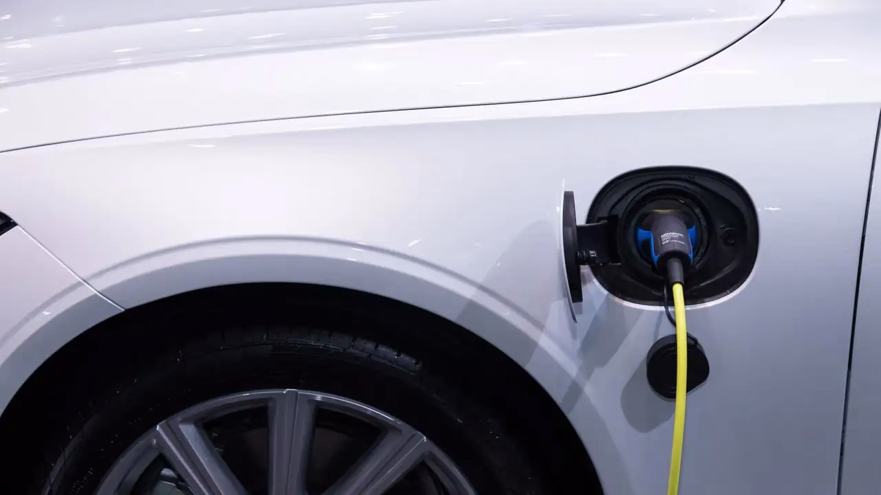 Gelbes Ladekabel steckt im Ladeanschluss eines weissen Elektroautos Gelbes Ladekabel steckt im Ladeanschluss eines weissen Elektroautos
