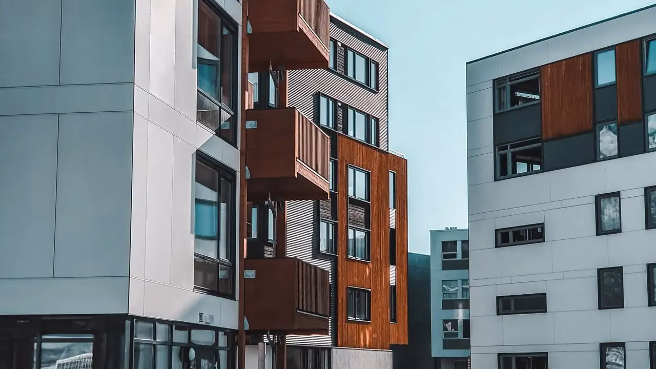 Moderne Wohngebäude mit hellen und braunen Fassadenelementen vor blauem Himmel