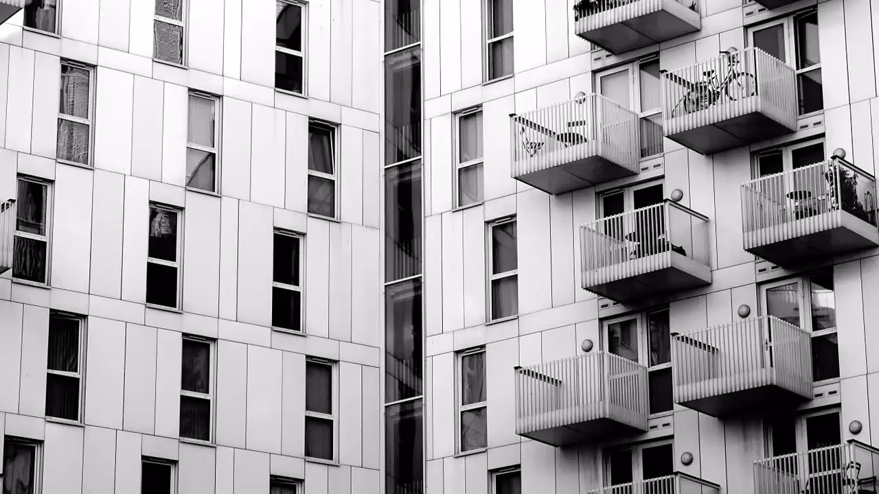 Schwarzweissaufnahme einer Wohnhausfassade mit Balkonen und Fahrrad