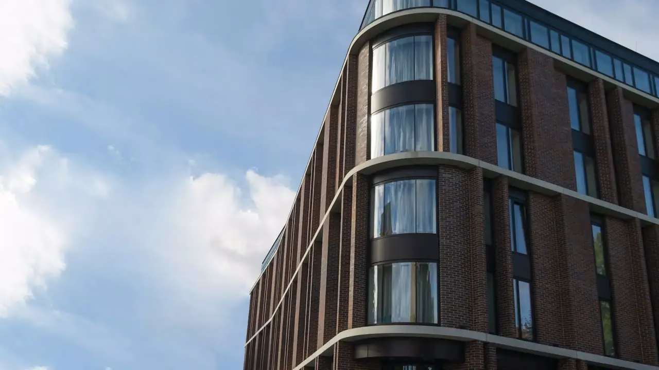 Gebäudeecke eines Backsteinhauses mit gerundeter Fassade vor bewölktem Himmel