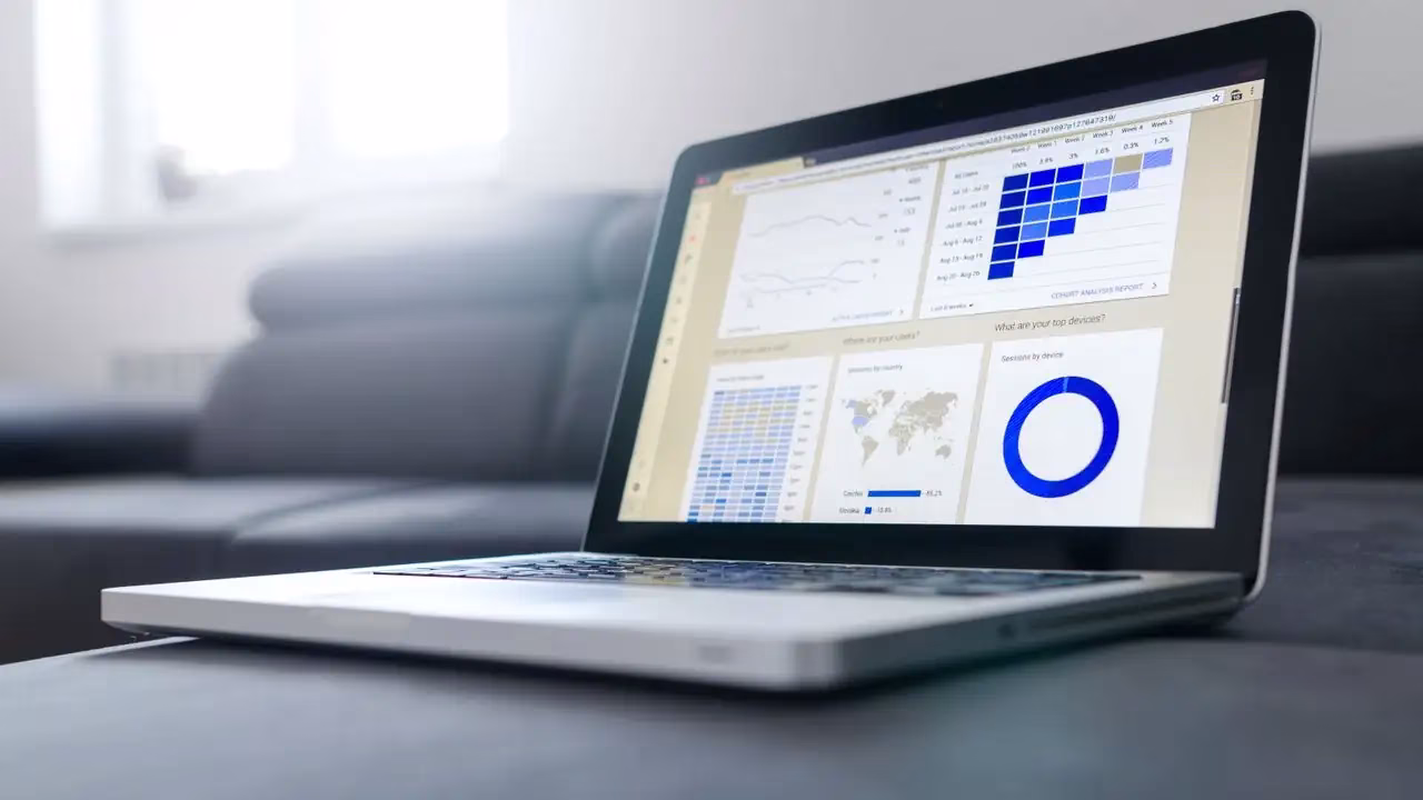 Laptop mit Dashboard aus Diagrammen auf einem Sofa in einem hellen Raum