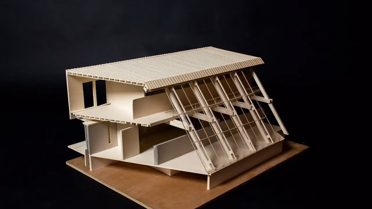 Architekturmodell eines Hauses mit Pultdach aus Karton vor dunklem Hintergrund