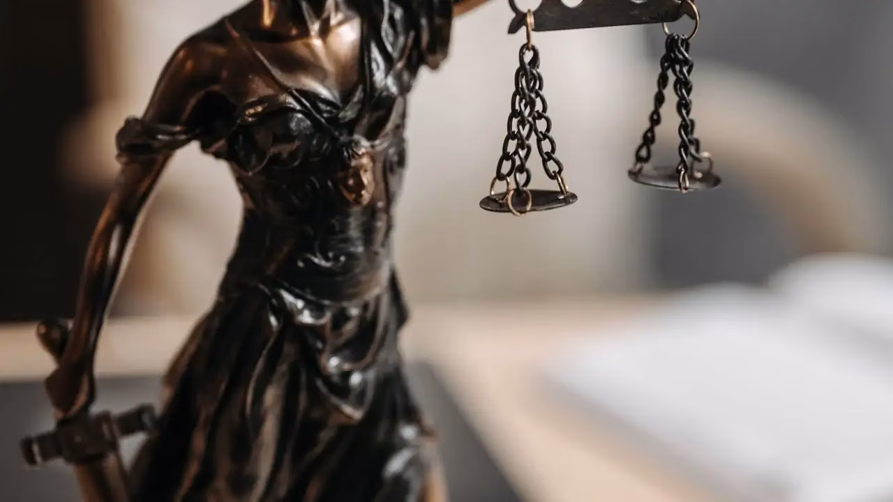 Bronzestatue der Justitia mit Waage vor unscharfem Hintergrund