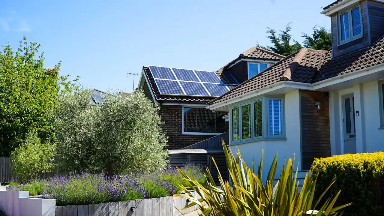 Wohnhaus mit Solarmodulen auf dem Dach hinter einem Garten Wohnhaus mit Solarmodulen auf dem Dach hinter einem Garten