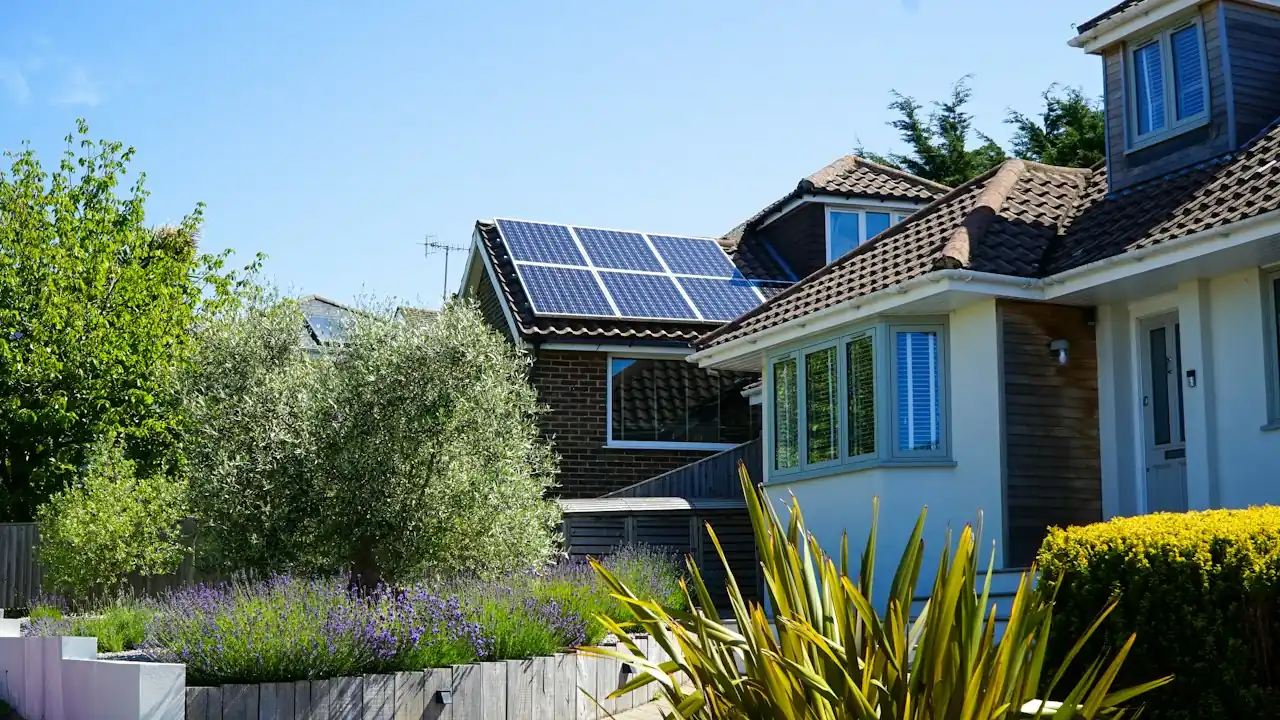 Wohnhaus mit Solarmodulen auf dem Dach hinter einem Garten