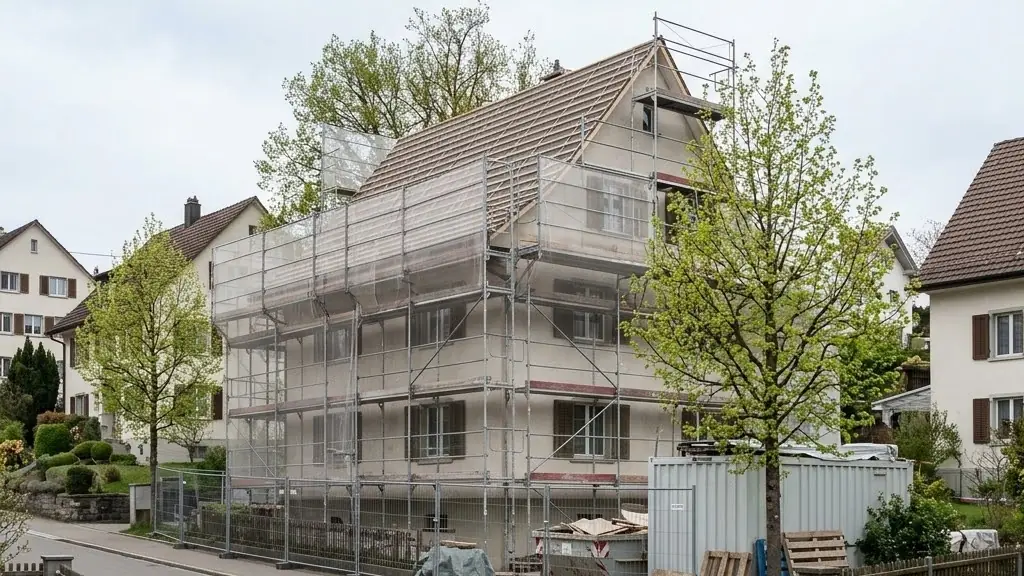 Eingerüstetes Einfamilienhaus in einer engen Quartierstrasse, Dach noch ohne Module