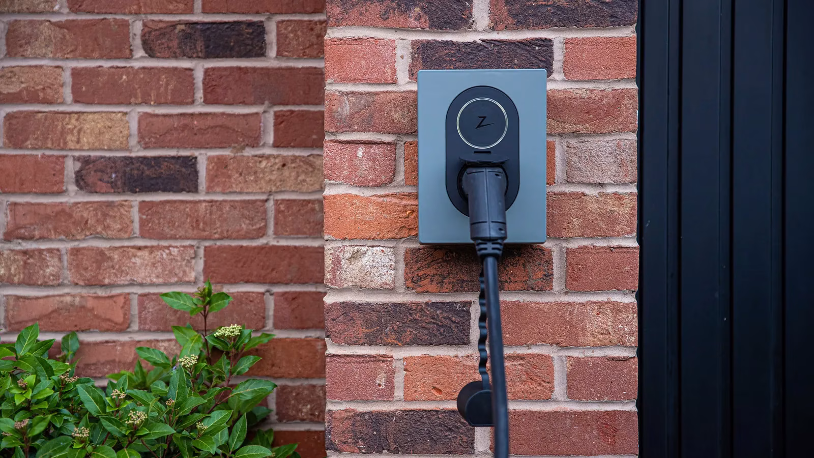 Zaptec-Wallbox an einer roten Backsteinfassade mit Ladekabel – Beispielbild